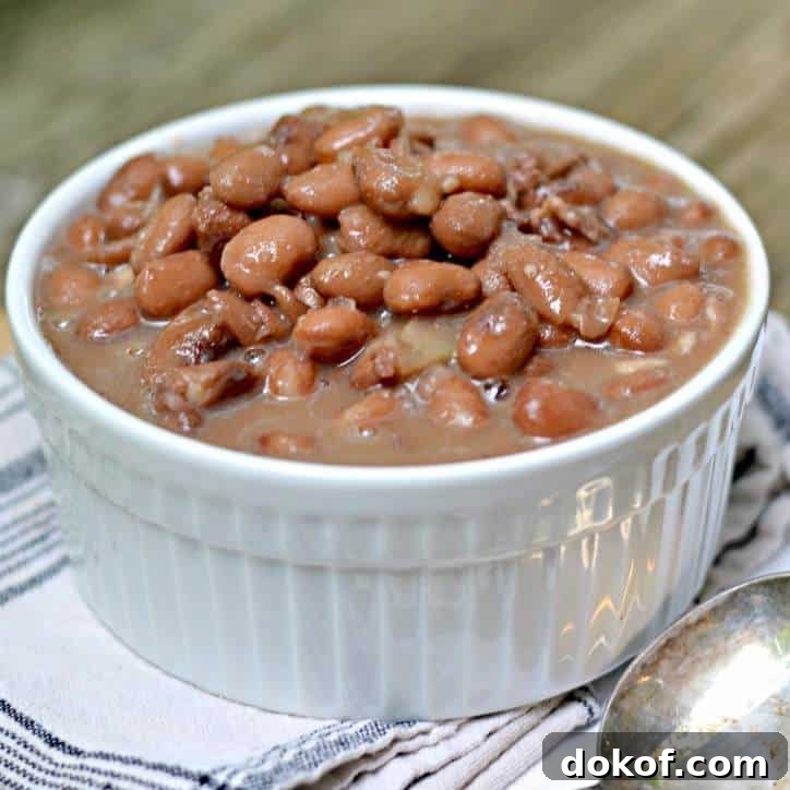Side view of a bowl of hot beans in a small white bowl with a spoon