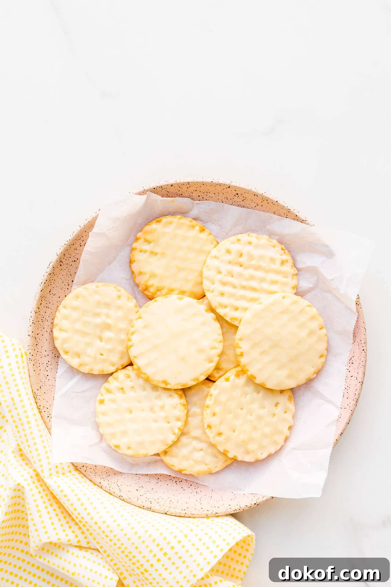 A pink ceramic plate with glazed lemon shortbread cookies.
