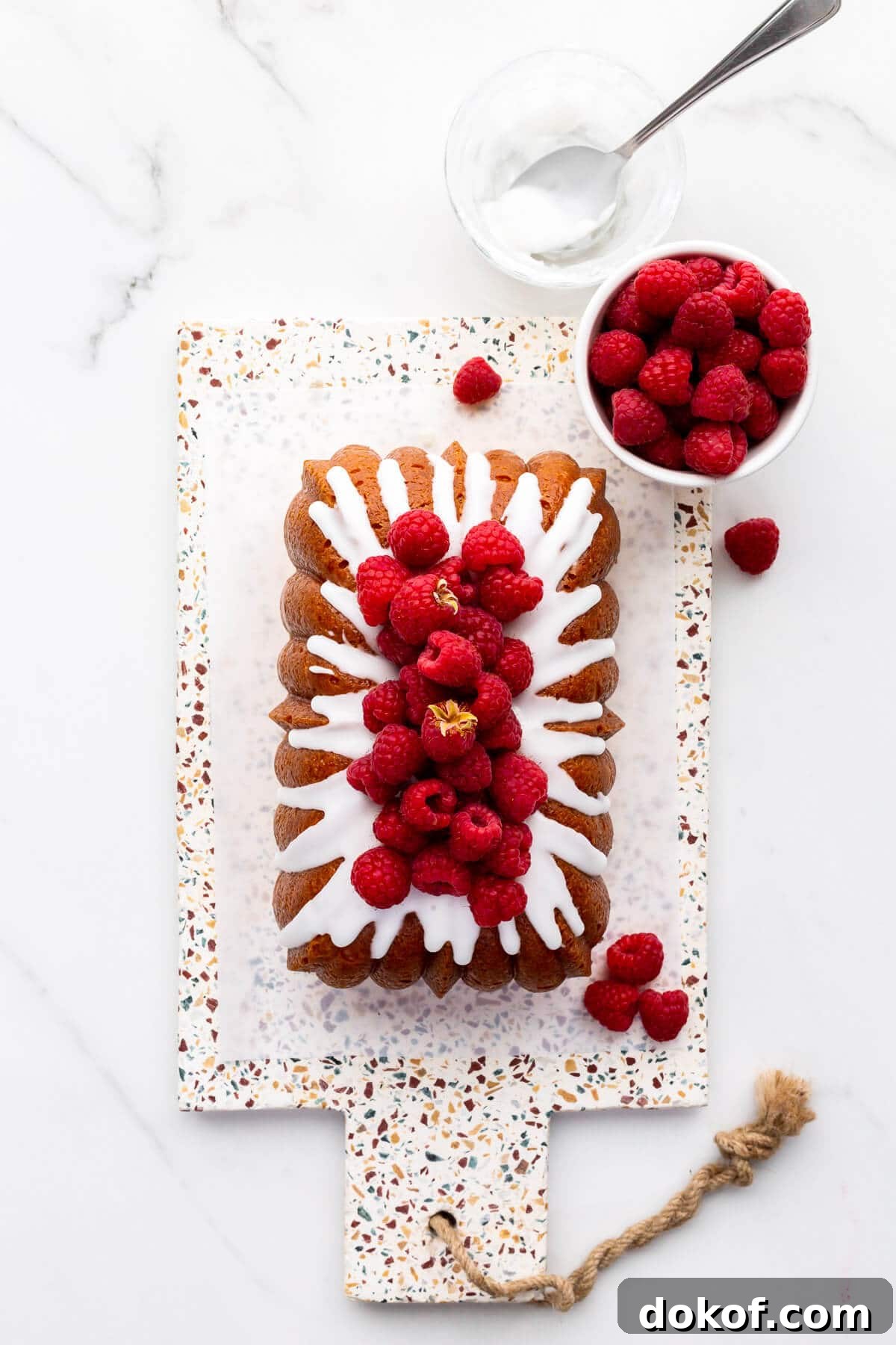 Lemon drizzle cake topped with icing and fresh raspberries.