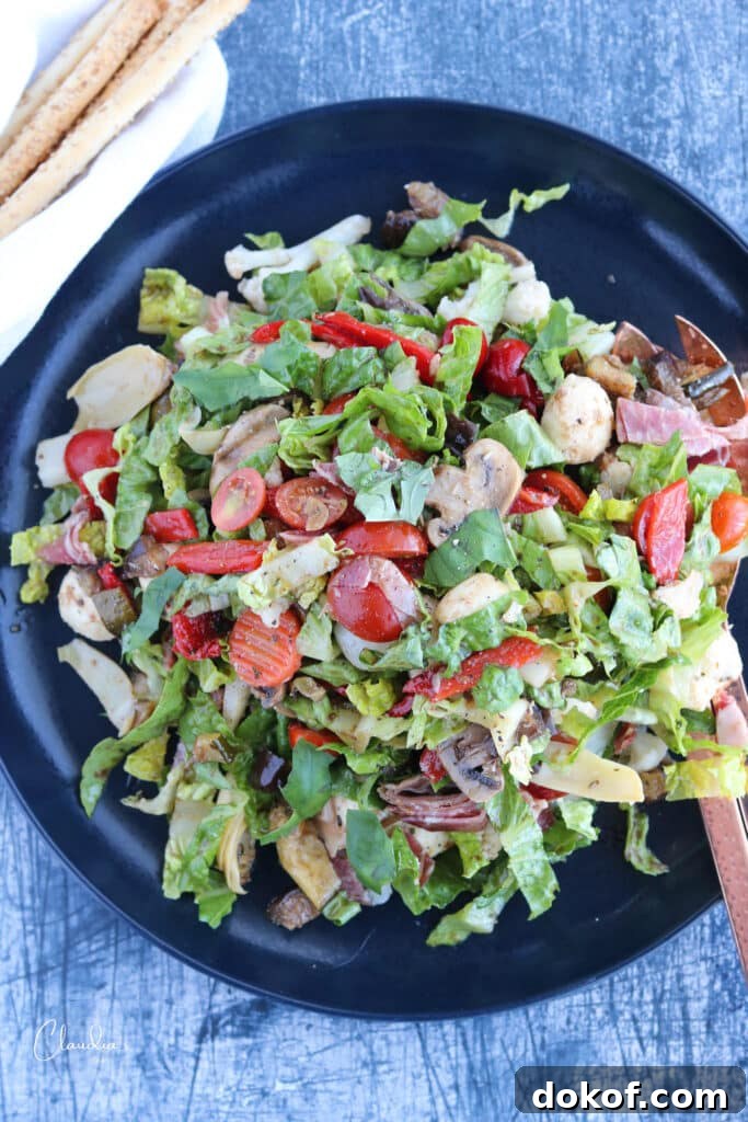 top view of chopped antipasto salad in blue platter with breadsticks