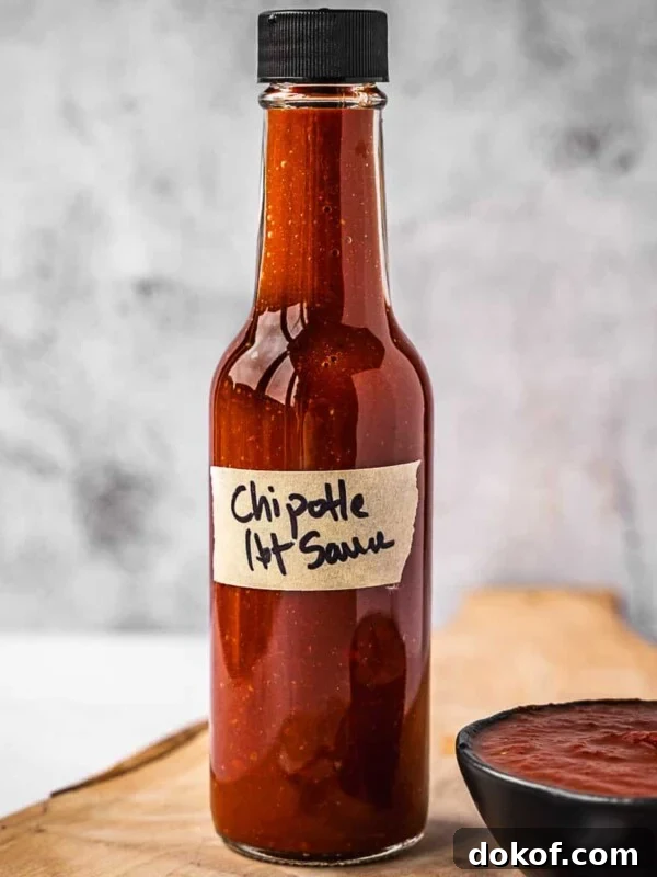 Bottle of hot sauce on a board next to a small bowl with the same hot sauce.