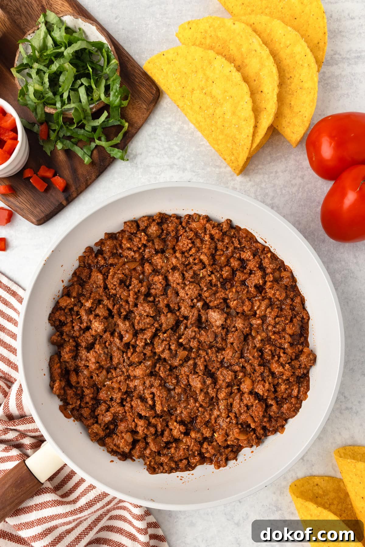 Cooked Taco meat in a skillet with shells on the side.