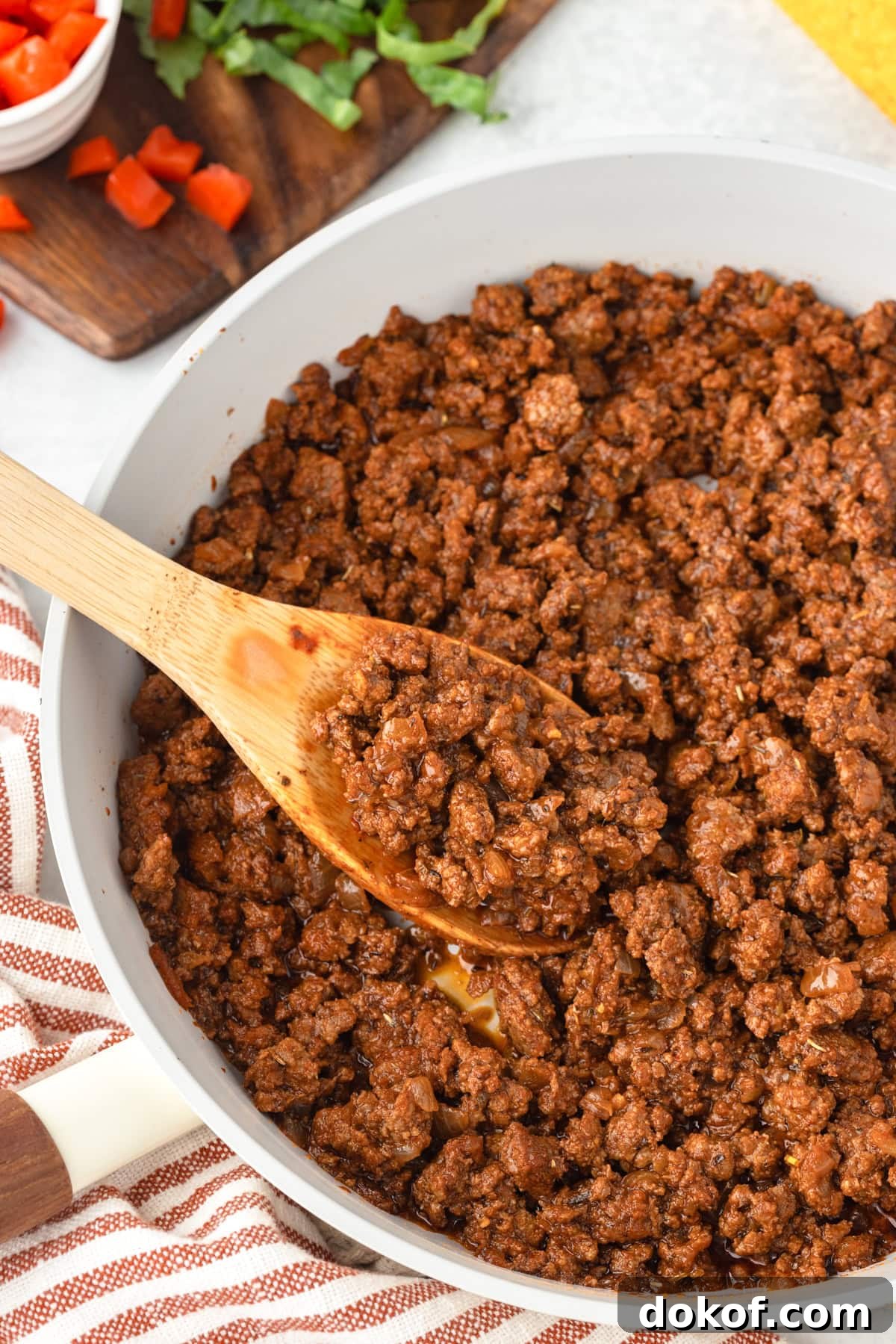 Taco meat in a skillet with a wooden spoon.