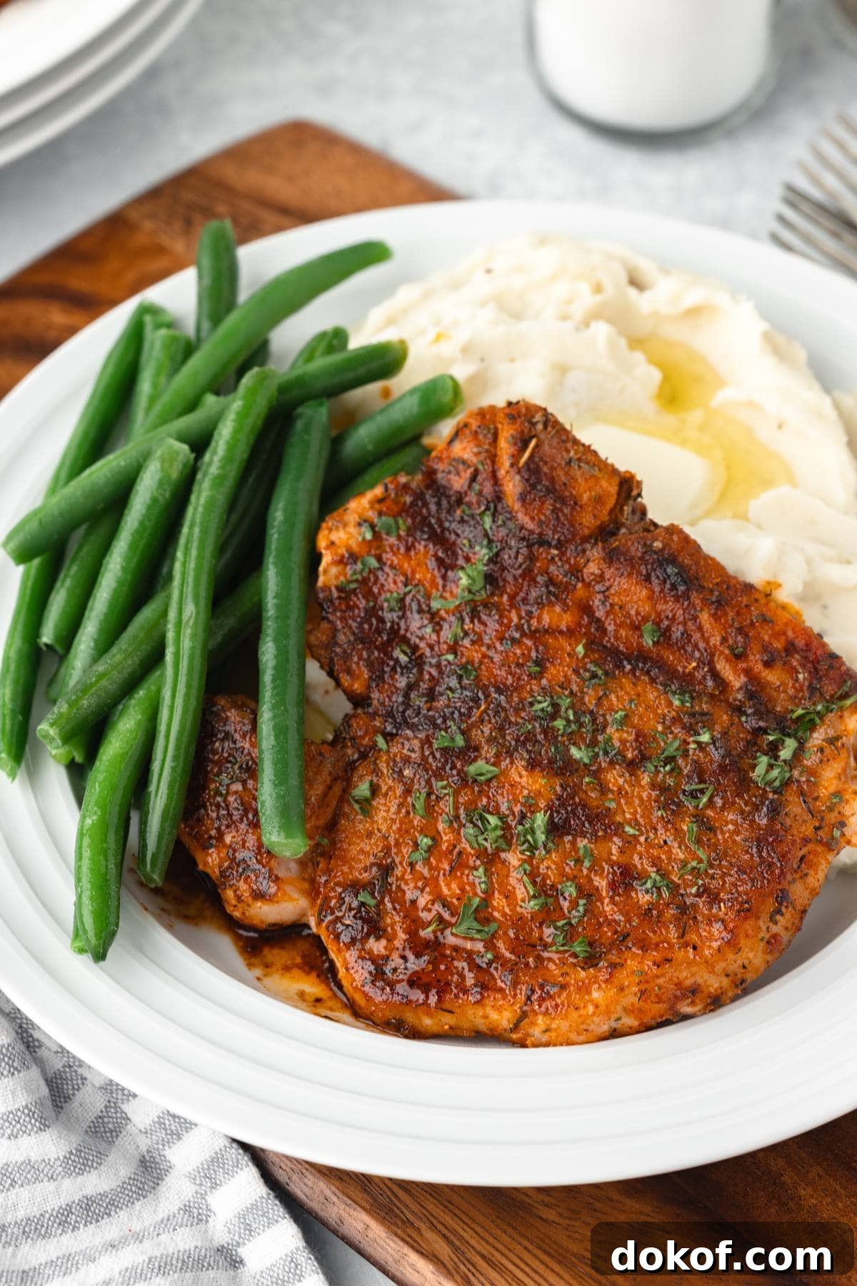 Bone-In Pork Chops with mashed potatoes and green beans on a white plate.