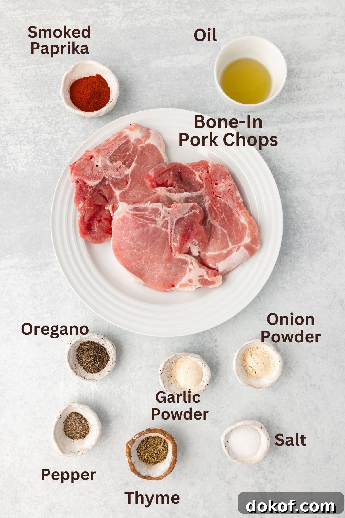 Smoked paprika, oil, and pork chops with seasonings on a white plate.