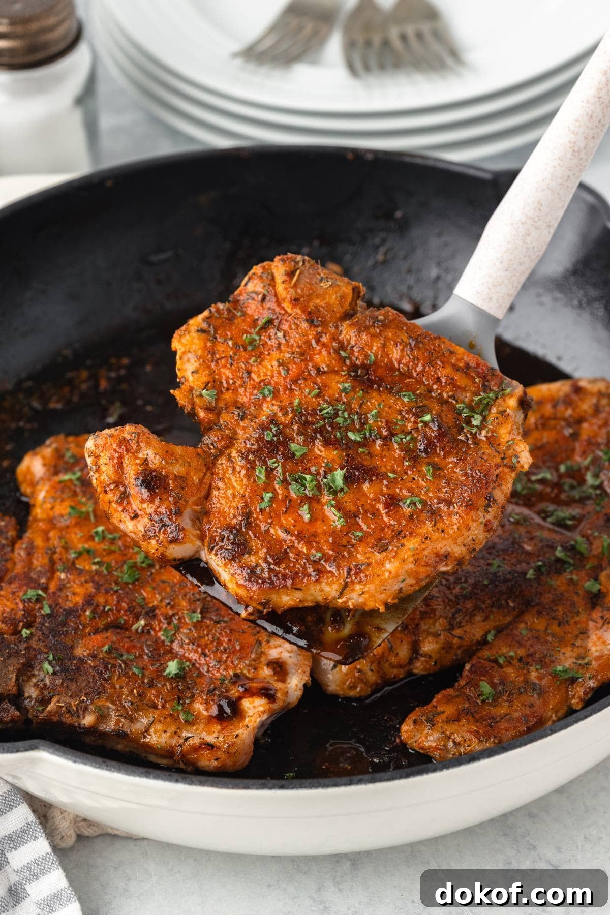 Juicy baked pork chop with sides on a white plate.