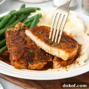 A cooked pork chop shown sliced in half with a fork in it.
