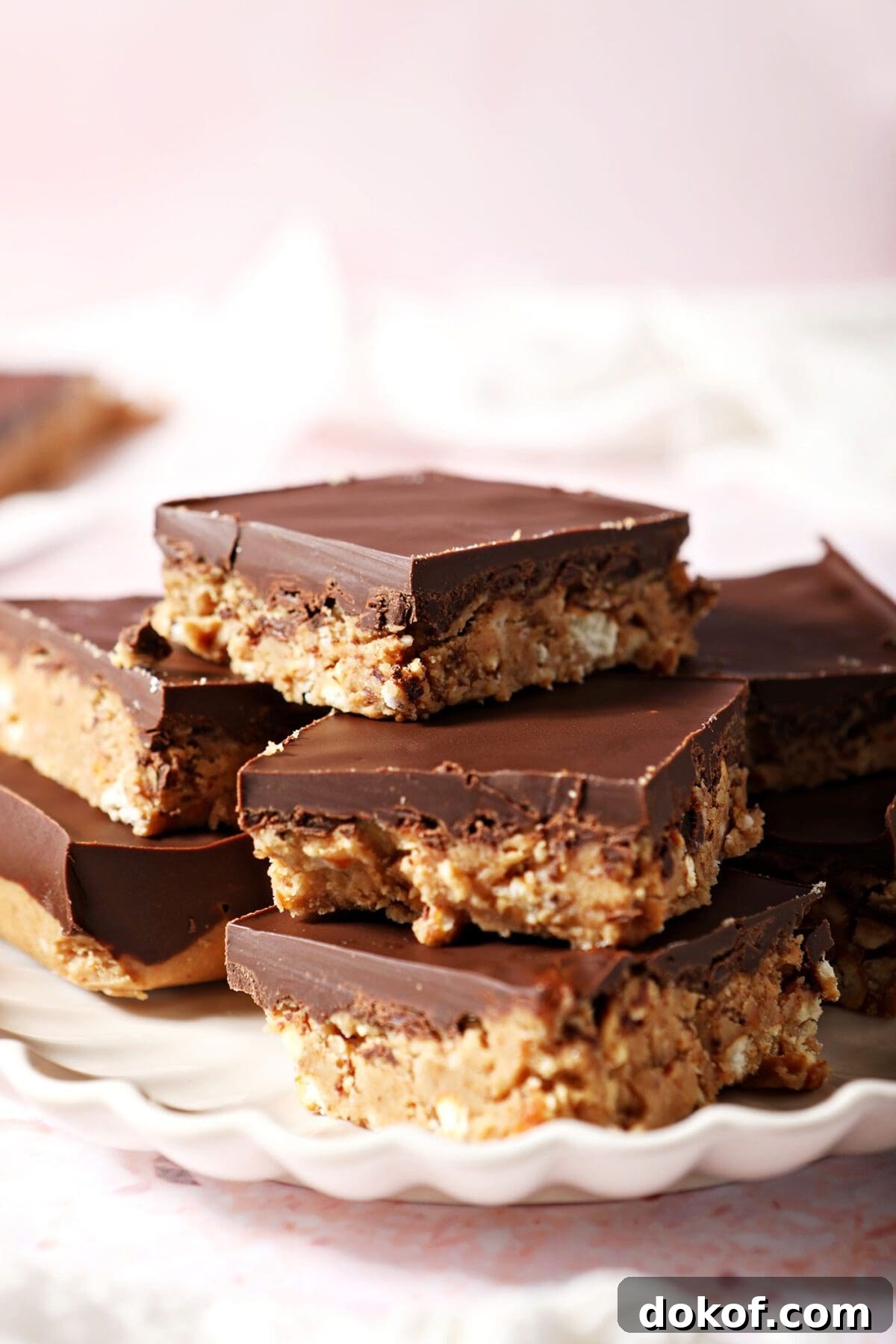 A scalloped plate holds a stack of Chocolate Peanut Butter Bars