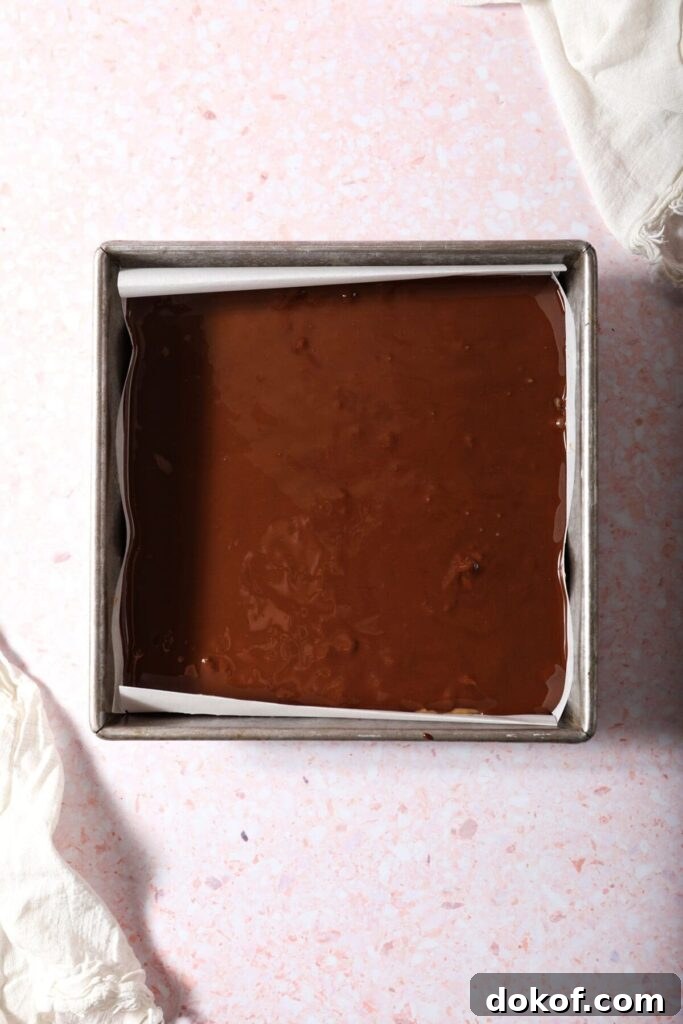 Hot chocolate coats the top of peanut butter bars in a square pan