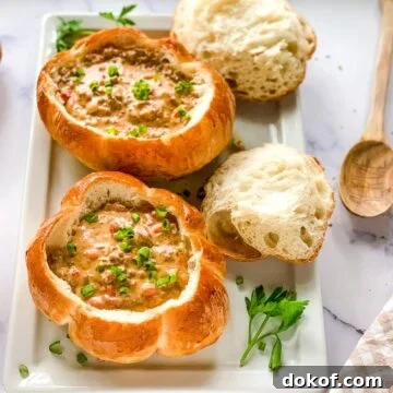 two bread bowls of cheeseburger soup on a white serving platter.