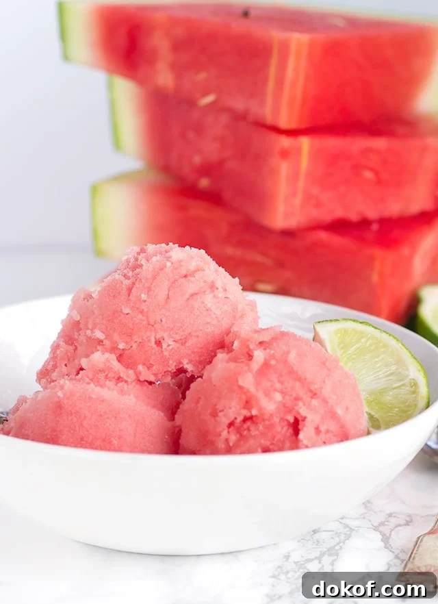 white bowl with fresh Watermelon Sorbet and a stack of fresh watermelon slices behind it