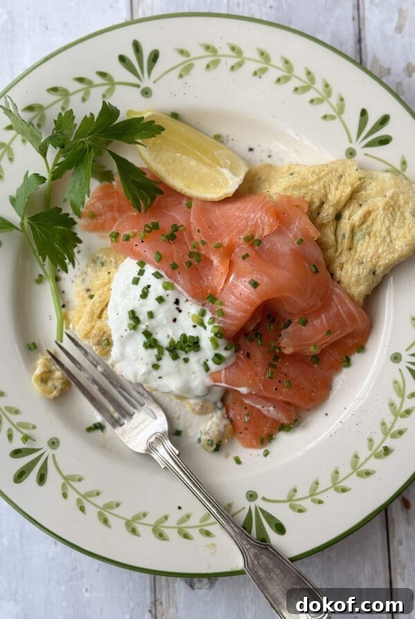 Morning Bagel Sandwich Recipes for Quick, Flavorful Breakfasts 13 salmon omelette on white plate with fork.