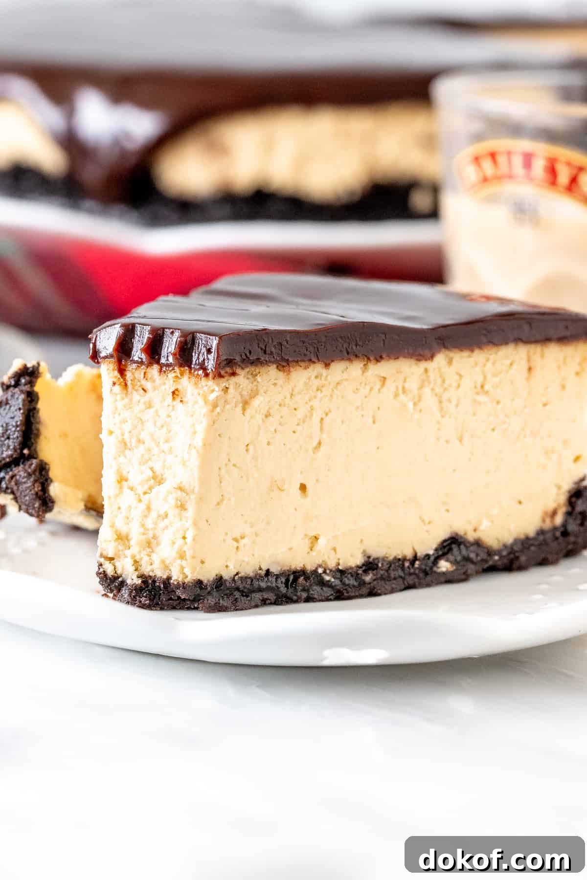 Slice of Baileys cheesecake with Oreo crust and chocolate ganache