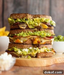 3 sandwiches stacked on each other with guac, cotija and chips blurred in background