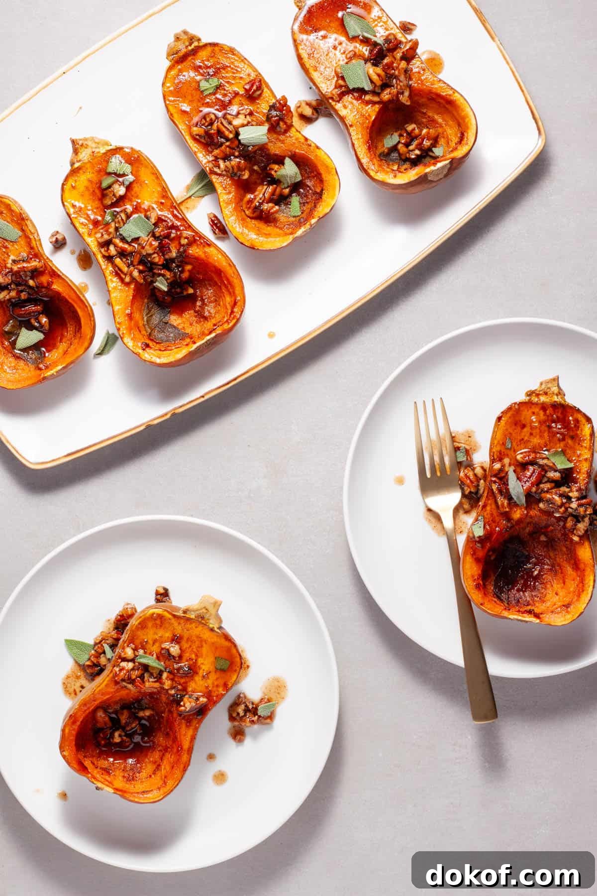 Roasted honeynut squash with maple pecans on a serving platter with a couple portions on smaller plates.