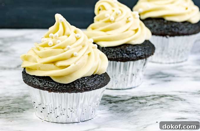 three Guinness Dark Chocolate Cupcakes with Irish Cream Cream Cheese Frosting in silver wrappers