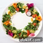 Midsummer Salad with greens, salmon, eggs and potatoes in a wreath shape on a white plate.