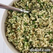 Barley salad with fresh herbs in a bowl with a spoon
