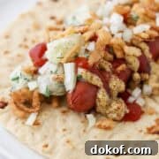 Hot dog on top of a tortilla topped with potato salad, onions, mustard and ketchup.