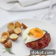 Beef Lindström on a plate topped with a fried egg next to roasted potatoes.