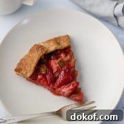 A slice of strawberry rhubarb galette on a plate with a fork