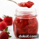 Close up of Strawberry Rhubarb Compote in a jar with a spoon.
